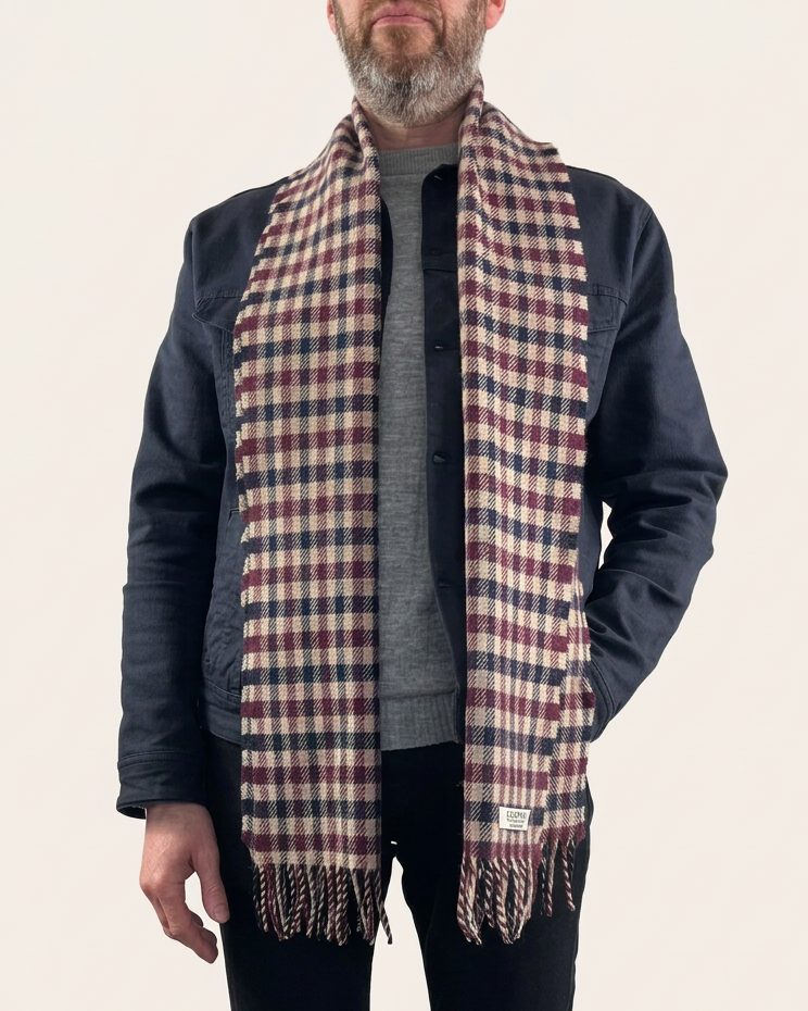Model wearing an Oliverman burgundy, navy and beige checked lambswool scarf against a cream background