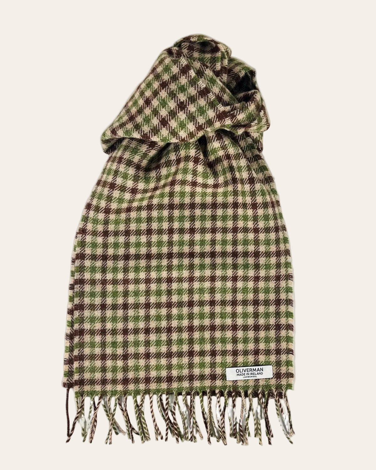 Oliverman brown, green and beige checked lambswool scarf with fringed ends, arranged on a cream background.